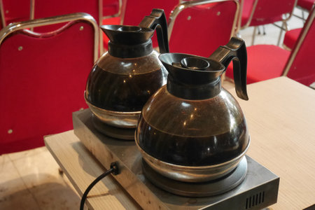 Two transparent glass kettles containing black coffee are on an electric heating stove.の写真素材
