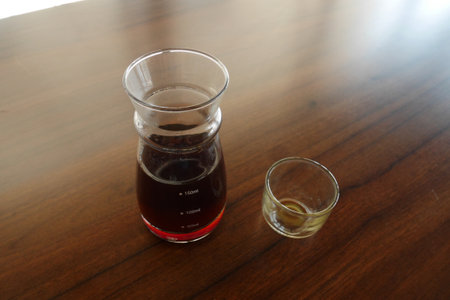 Americano black coffee is served on the table using a laboratory measuring cup and a small transparent glassの写真素材