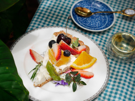 Beautiful cheesecake with fresh fruits and gold spoon background on polka dot tableclothの写真素材