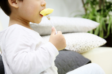 A child eating apples with a forkの写真素材