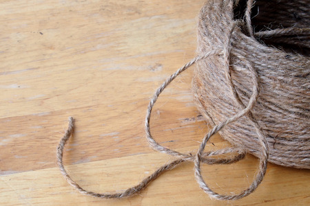 Close up roll of a brown rope on wood plate, view from above.の写真素材