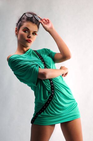 smiling girl posing in a green dress with glassesの写真素材