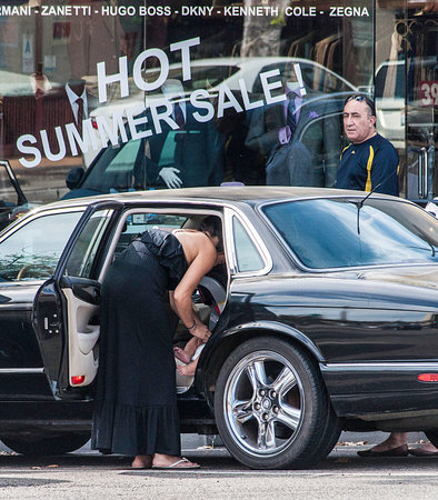 Mom changing baby's diaper on back seat of Jaguar on city street.のeditorial素材