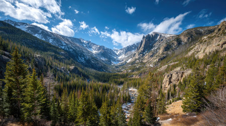 A photograph of Rocky Mountains wilderness with rocky mountain valley viewpoint, fir tree groves,...