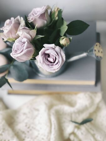 shabby light pink roses  in water pot standing on booksのeditorial素材