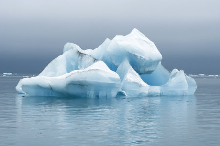 A large iceberg emerges from calm Arctic waters, reflecting soft light under a cloudy sky. This serene scene showcases the beauty of nature in a remote region. Generative AIの素材