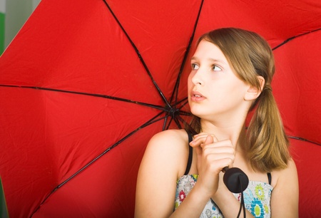 Teen with red umbrella is listening to the sound of falling drops od rain の写真素材