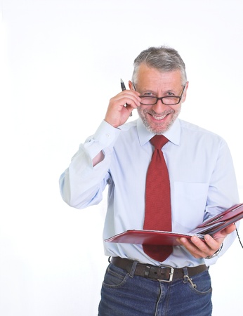 Vertical image presents graying white man, wearing blue shirt and tie, who stands, laughing,  with a folder of papers and pen in his hands.の写真素材