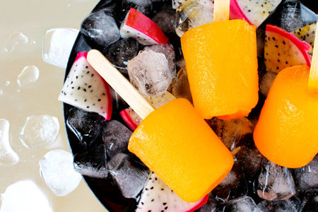 orange  and slice dragon fruit on ice cube on black dish,ice cream on chrome backgroundの写真素材