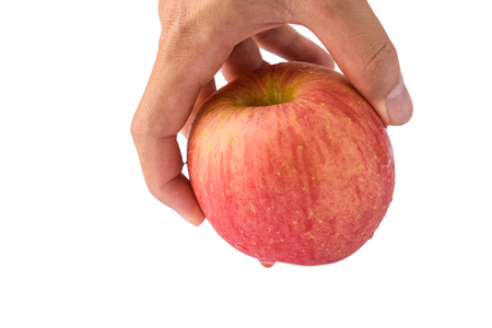 Hand holding the pink "Fuji" apple.Isolated on white background.Keep from the floorの写真素材