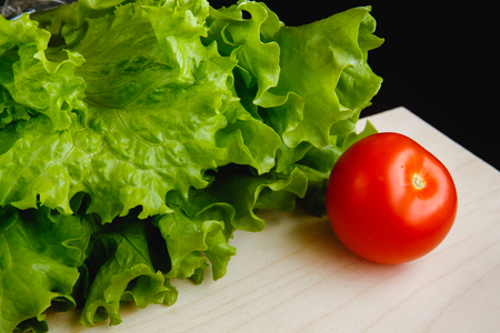 Fresh vegetables on the table:  lettuce,  tomatoes. Cutting boardの写真素材