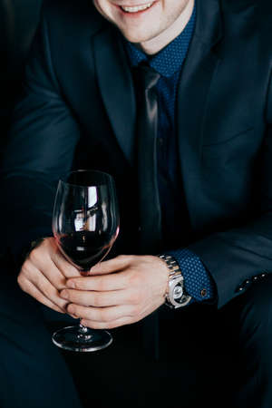 successful man keeps watch and clothes With a glass of red wineの写真素材