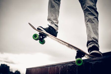 skateboarder guy is getting ready for the trick on the skateboard and slides on the counter. High contrast and monochrome filter with glare.の写真素材