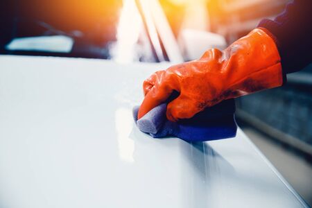Worker Hands hold sponge for washing car cleaning white car. Concept manual car wash for cars.の写真素材