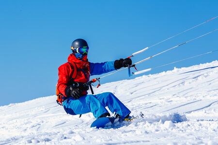 Snowboarder with a kite on fresh snow in the winter in the tundra of Russia against a clear blue sky. Teriberka, Kola Peninsula, Russia. Concept of winter sports snowkite.の写真素材
