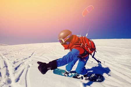 Snowboarder with a kite on fresh snow in the winter in the tundra of Russia against a clear blue sky. Teriberka, Kola Peninsula, Russia. Concept of winter sports snowkite.の写真素材