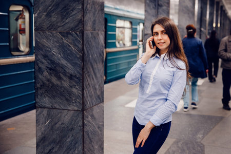 Young girl tourist talking on the phone in the subway and smiling. The concept is always in touch.