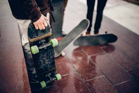 Male skateboarder man holds a skate board in his hand against the background of a team of team...