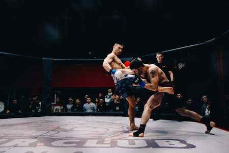 TOMSK, RUSSIA - February 12, 2017: GRAND PRIX  Power Club on MMA. Boxers fighters  fight in fights without rules in the ring octagon. Dark background. High contrast and monochrome color tone.のeditorial素材