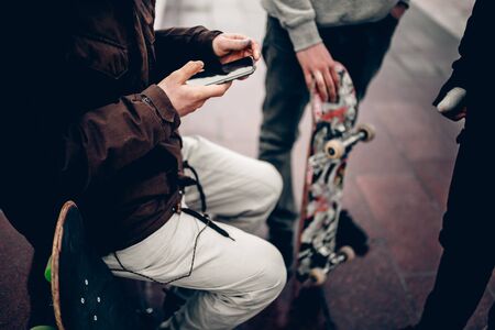 guy is holding the phone on the background Friends of the company of men holding their hands skateboards. Concept group of street athletes students social networkの写真素材