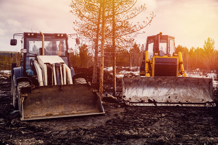 Tractor loader and bulldozer on a caterpillar drive is parked in the mud. Concept road construction.の写真素材