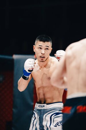 TOMSK, RUSSIA - February 12, 2017: GRAND PRIX  Power Club on MMA. Boxers fighters  fight in fights without rules in the ring octagon. Dark background. High contrast and monochrome color tone.のeditorial素材