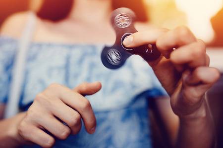 Girl to play with Fidget Spinner in his hands, the concept of relieving stress, develop a small hand mathematics.の写真素材