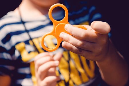 Child boy to play with Fidget Spinner in his hands, the concept of relieving stress, develop a small hand mathematics.の写真素材