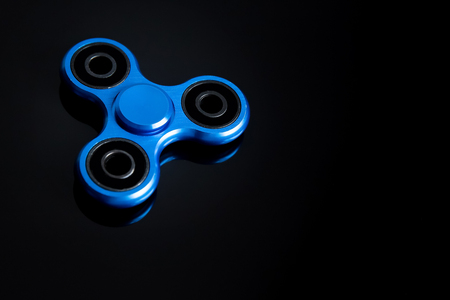 Fidget finger spinner, anxiety relief toy on black background, copyspace. Concept relieving stressの写真素材