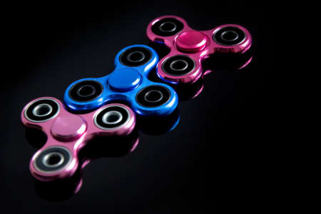 Fidget finger metal spinner, anxiety relief toy on black background, copyspace. Concept relieving stressの写真素材