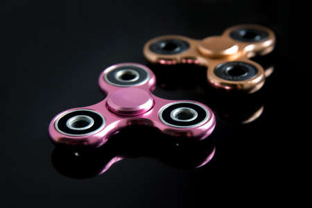 Fidget finger metal spinner, anxiety relief toy on black background, copyspace. Concept relieving stressの写真素材