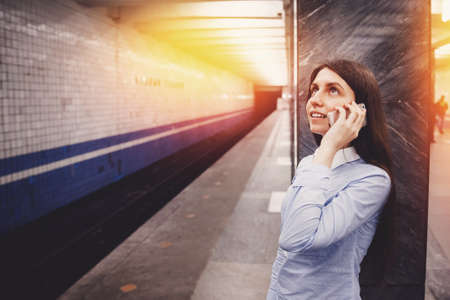 Young girl tourist talking on the phone in the subway and smiling. The concept is always in touch.の写真素材