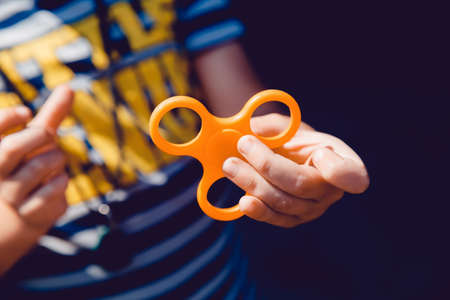 Child boy to play with Fidget Spinner in his hands, the concept of relieving stress, develop a small hand mathematics.の写真素材