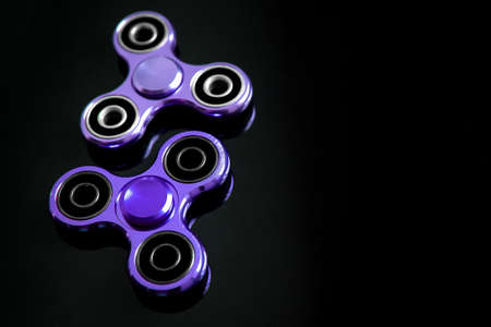 Fidget finger metal spinner, anxiety relief toy on black background, copyspace. Concept relieving stressの写真素材