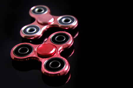 Fidget finger metal spinner, anxiety relief toy on black background, copyspace. Concept relieving stressの写真素材
