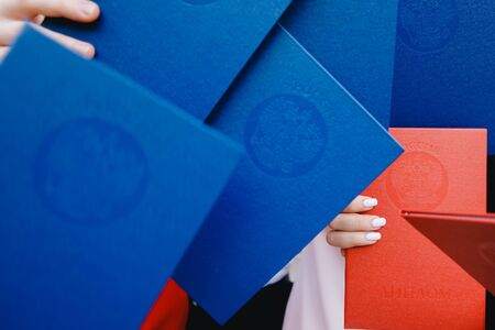 Red and blue diplomas of Higher Education University in hands Russia. Inscriptions in Russian: Russia. Diplomaの写真素材