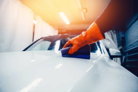 Worker cleaning white car. Concept manual car wash for cars.Toning and a ray of light.の写真素材