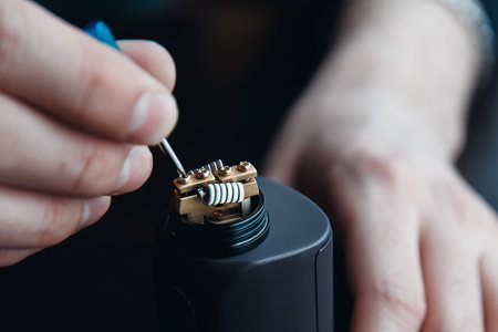male master installs a coyle. Spiral for electronic evaporator and cigarette. Vape, vaping. Firing a coil.の写真素材