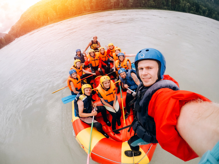 mountain Altai, RUSSIA - July 16, 2017: man in a helmet holds an action camera and makes selfie on the background of friends with oars, raftingのeditorial素材