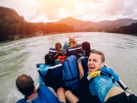 tourist man sitting in a boat and happy, a boat with a motor rides at high speed along the river. Concept raftingの写真素材