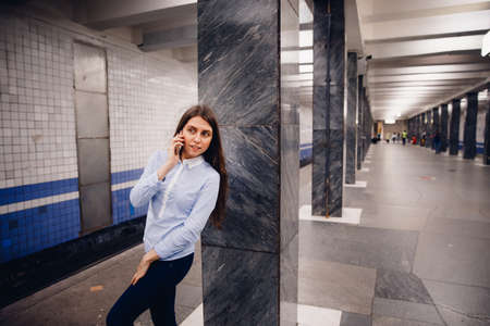 Young girl tourist talking on the phone in the subway and smiling. The concept is always in touch.の写真素材