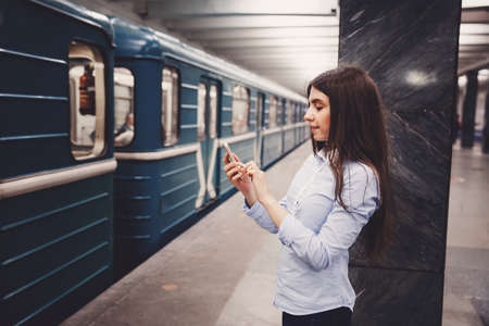 Young girl tourist talking on the phone in the subway and smiling. The concept is always in touch.の写真素材
