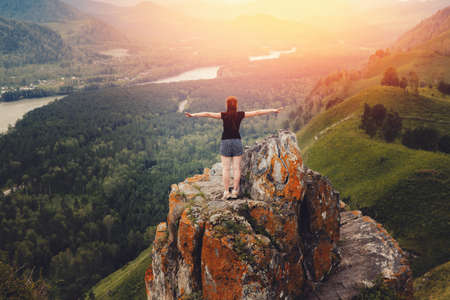 girl traveler stands on the top of the rock of the damn finger in the mountainous Altai, Russia and rejoices. Concept to succeedの写真素材