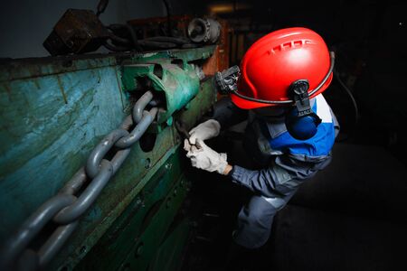 male miner in a underground mine is repairing a harvester, a sinker. Concept work in difficult conditions.の写真素材