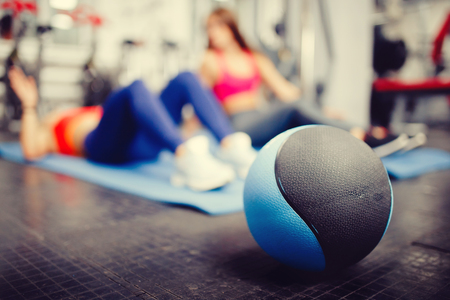 Close-up of a medical ball on the background of people who are engaged in fitness in the gym. copyspaceの写真素材