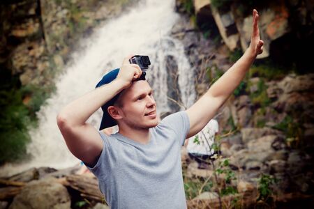 Tourist traveler with an action camera Go on his head in the background waterfall in Vietnam. concept of extreme holidays in the mountains.の写真素材