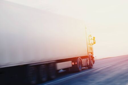 truck at sunset in motion carries cargo, a container. Concept logistics, transportation, transportation, business.の写真素材