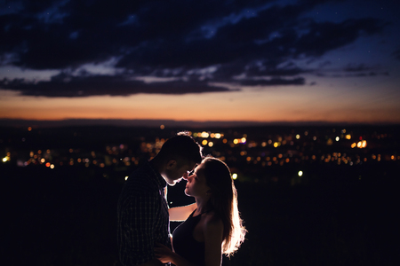 Lovers man and girl against background night city, night starry sky and horizon. Concept date Valentines Day, first kiss love.の写真素材