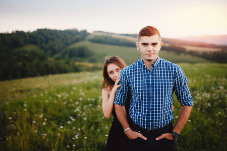 Lovers stand against the background of mountains and hills embracing. Concept protection of his family, girls, beloved, brides, war, protection, support, help in relationships, stoneの写真素材