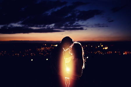 Texture with background for love: silhouette of loving couple against background of night city lights. Concept first love, feelings without boundaries, touch and flight of soul and consciousnessの写真素材